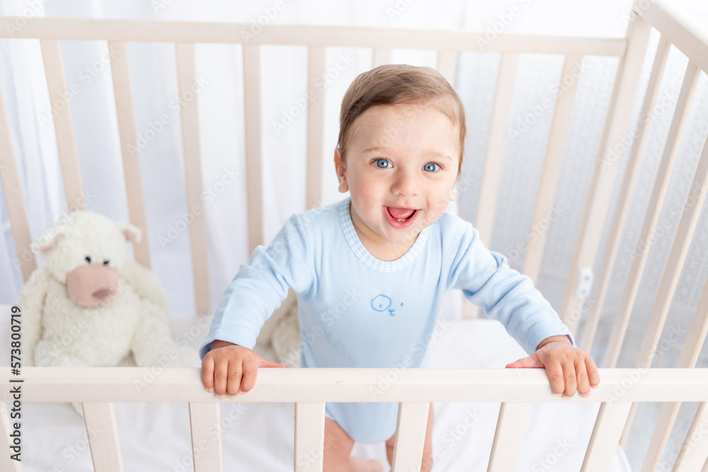 portrait of a baby boy in a crib in a children's room with big blue eyes
