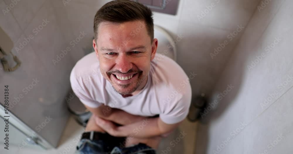 Portrait of smiling man sitting on toilet with joyful emotions on face Portrait of smiling man sitting on toilet with joyful emotions on face