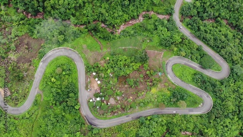Aerial top view above the mountain road. Car driving through the curve.