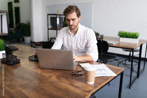 young businessman man in a white shirt works on laptops in the office © Ivan Traimak