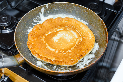 American Pancake burn on the pan,homemade pancake fried in a pan in the kitchen.Delicious thin pancake in frying pan on gas stove.Closeup.