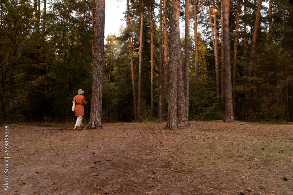 Fototapeta premium Unrecognisable woman in hat and linen wear at walk in forest