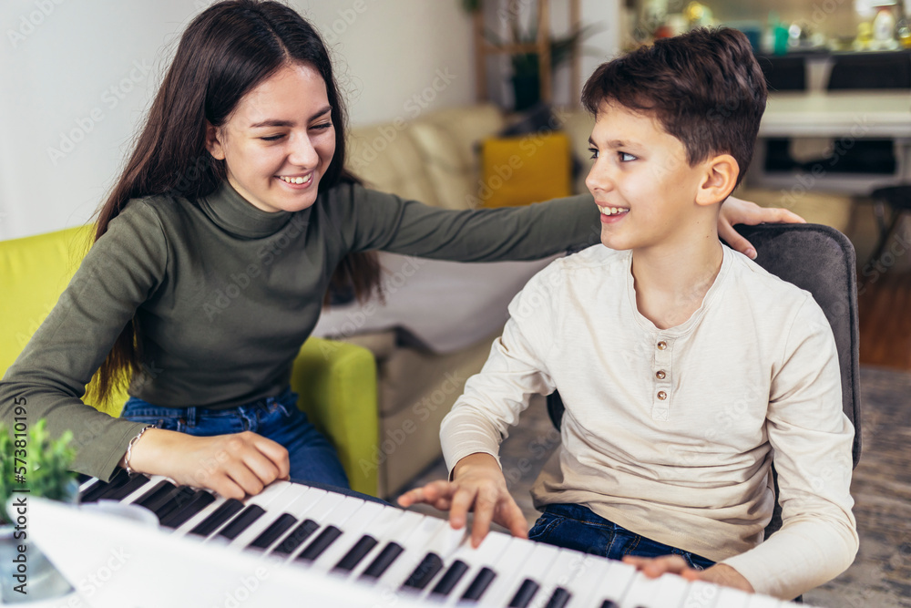 Fototapeta premium Brother and sister play electric piano at home and have fun.