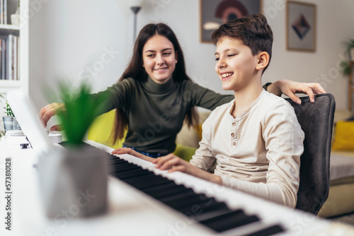 Brother and sister play electric piano at home and have fun.
