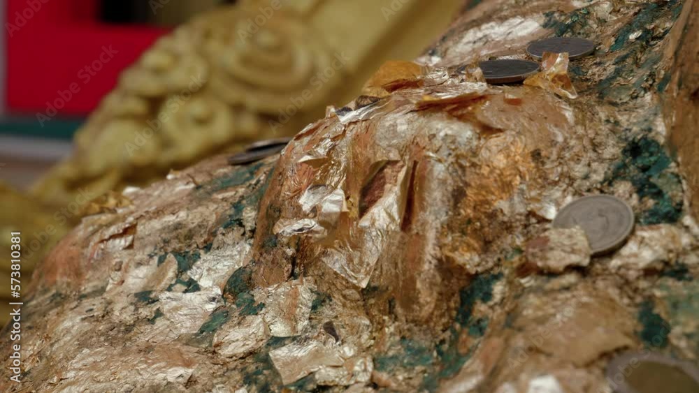 Close up view of Buddha statue with offering of coins for good luck at Buddhist temple, Thailand Close up view of Buddha statue with offering of coins for good luck at Buddhist temple, Thailand