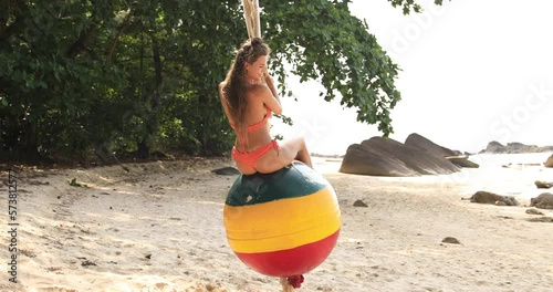 Woman swinging on swings made from old buoy on the beach