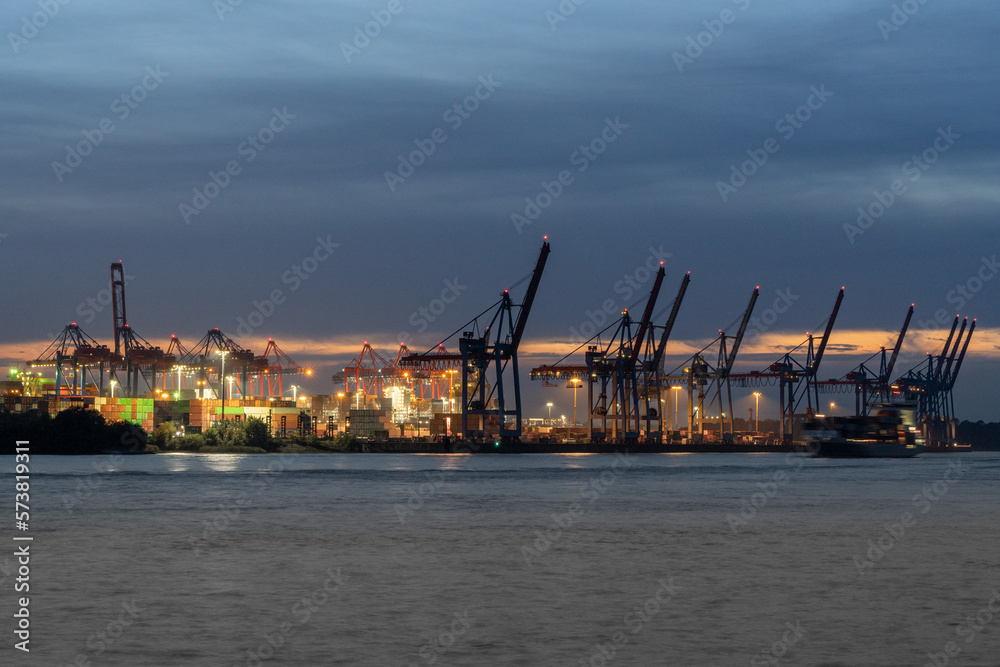 Hafenkräne im Hamburger Hafen während der blauen Stunde bei leicht bewölktem Himmel, horizontal 