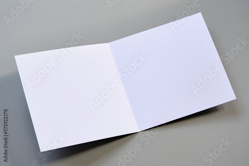 Laying blank open empty square greeting card mock up on grey background. For use as a Christmas, birthday, wedding or celebration background template.	
