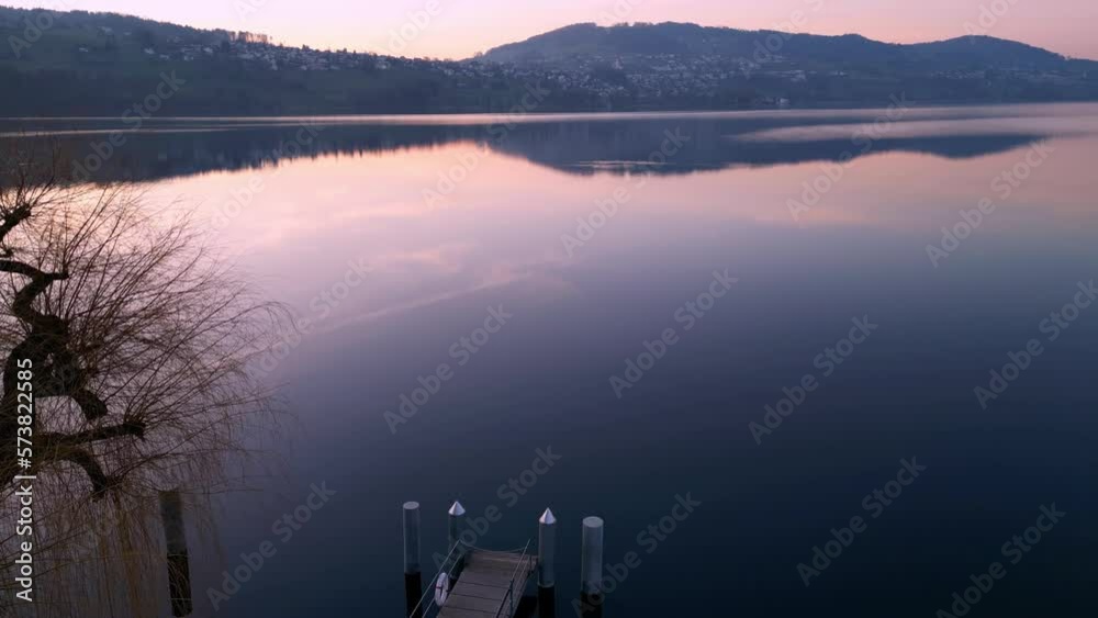 Flying over a dock and over a calm lake at sunset in Switzerland.