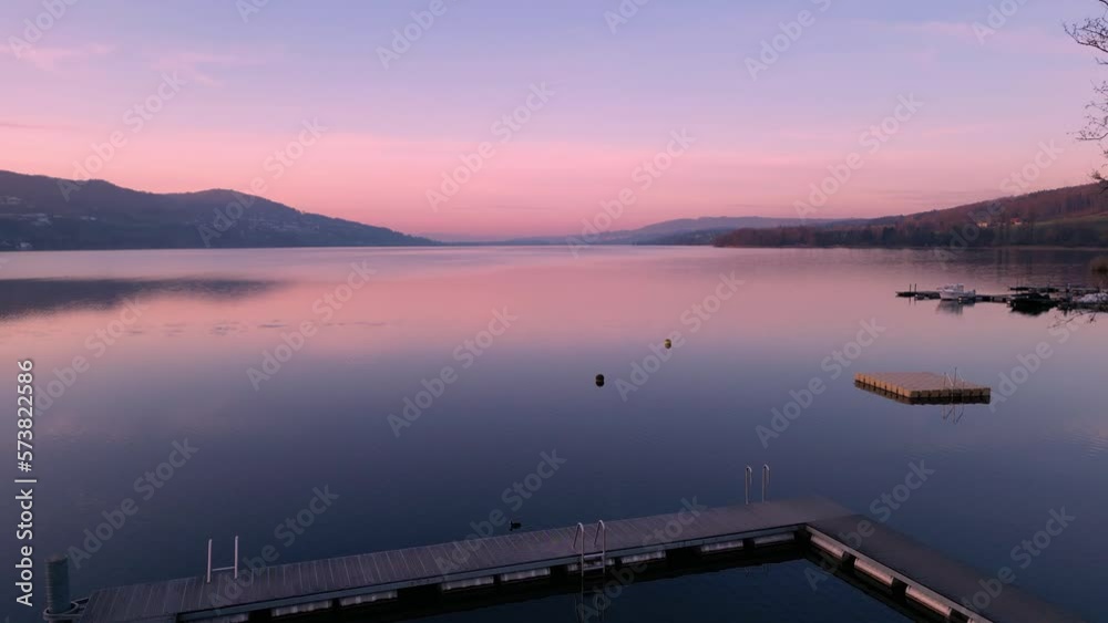 Flying over a swimming dock and out to a lake at sunset in Switzerland.