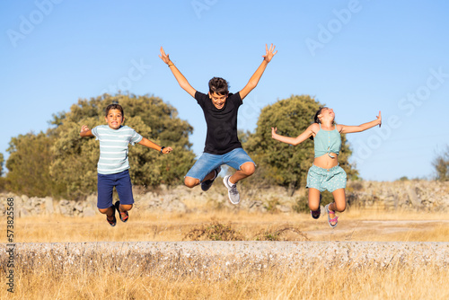 Three funny kids jumping on a field on a summer day