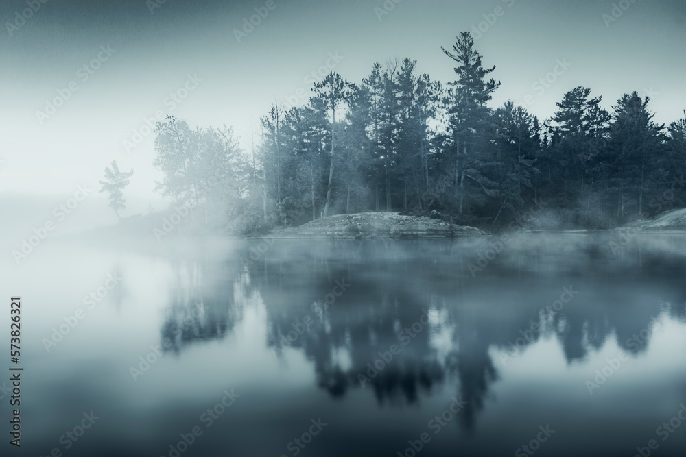 Forest in fog reflecting in lake Forest in fog reflecting in lake