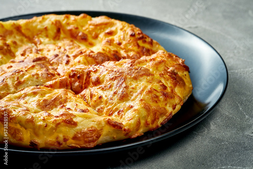 Khachapuri with salty melted cheese in a plate. Concrete background