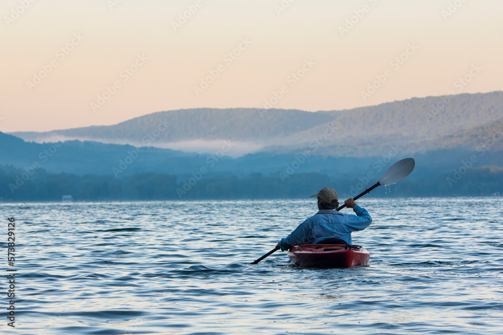 Man kayaking at sunrise on Skaneateles Lake, Skaneateles, New York State, USA Man kayaking at sunrise on Skaneateles Lake, Skaneateles, New York State, USA