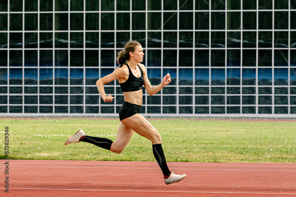 female athlete running track stadium in background glass facade building