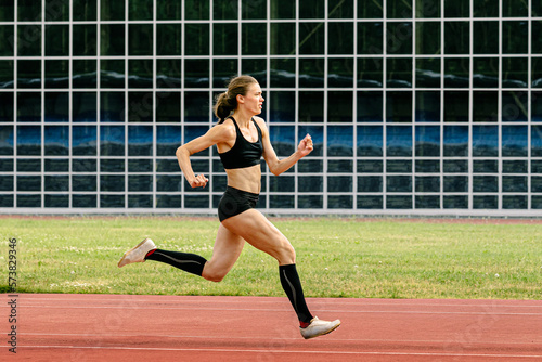 female athlete running track stadium in background glass facade building