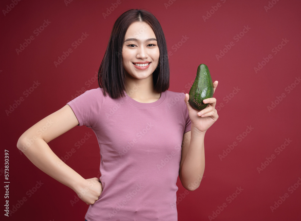 Young Asian woman holding avocado fruit on background Young Asian woman holding avocado fruit on background