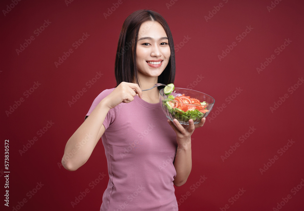 Young Asian woman eating salad on background Young Asian woman eating salad on background