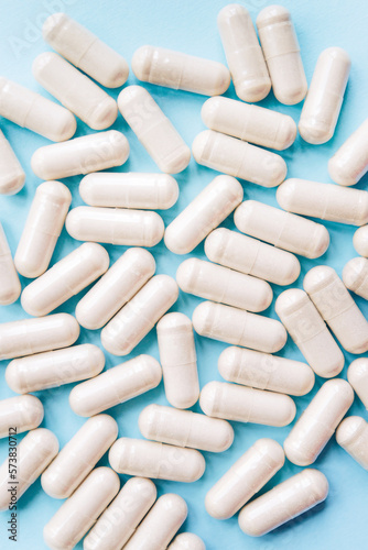 Scattered white pill capsules on a blue table. Model special offers as advertising, web background or other ideas. concept of medicine, pharmacy and healthcare. copyright. Empty place for text or logo