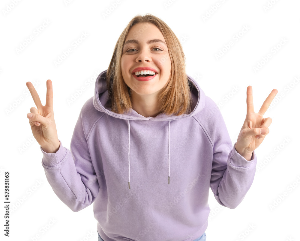 Young woman in lilac hoodie showing victory gesture on white background Young woman in lilac hoodie showing victory gesture on white background