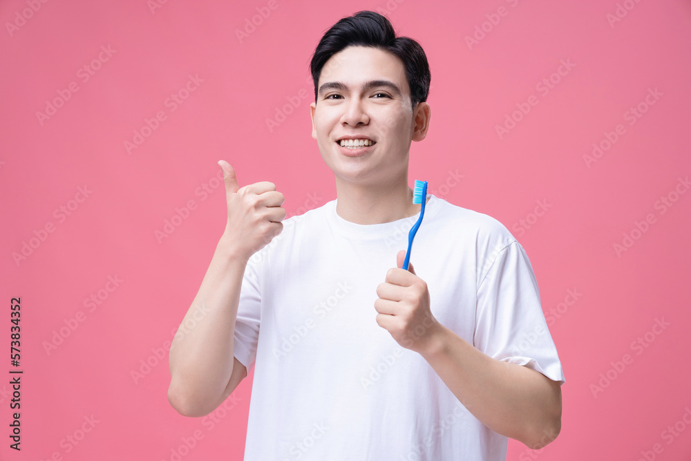 Young Asian man holding toothbrush on background Young Asian man holding toothbrush on background