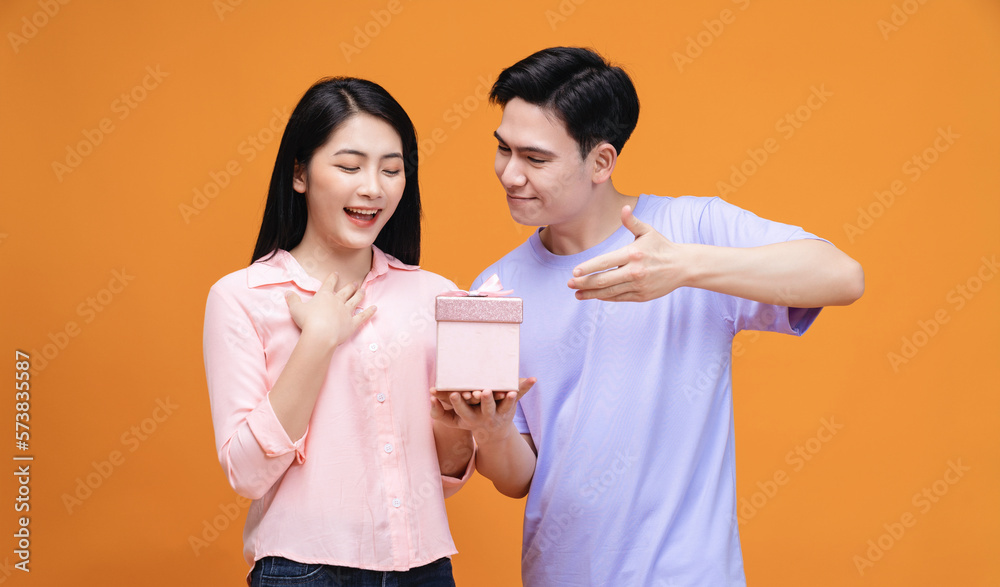 Young Asian couple with gift box on background Young Asian couple with gift box on background