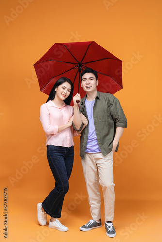 Young Asian couple with umbrella on background