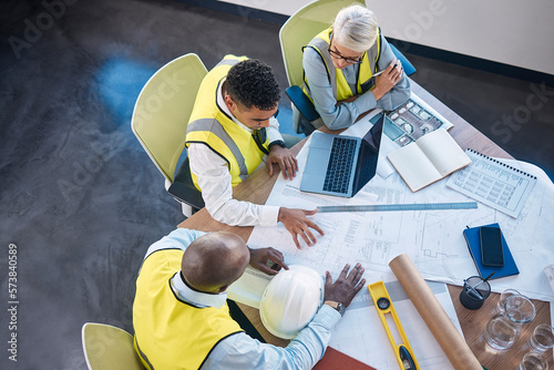 Architect, laptop and team in meeting above for construction or building planning strategy at office. Group of diverse engineers discussing floor plan, project layout or blueprints for architecture