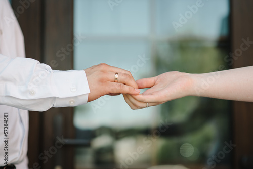The Bride and groom holding hands. Rings. Engagement. Hands are newlyweds with wedding rings. Men's ring with ornament. Women's ring with stones.
