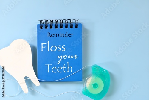 Obraz na płótnie Floss your teeth reminder on blue notepad. Dental and oral health care concept. w salonie