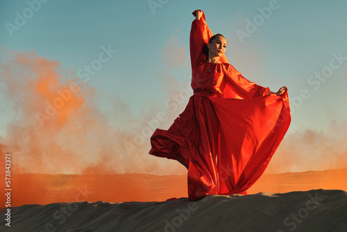 Woman in red dress dancing in the desert