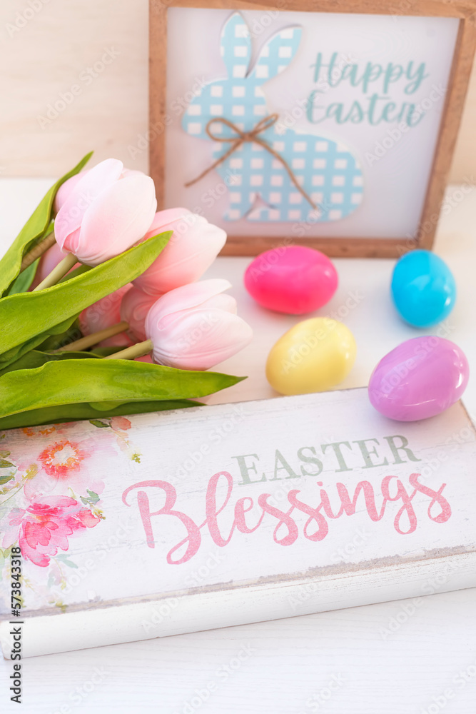 Easter background. Pink flowers tulips. bright colored eggs and a wooden sign with the inscription happy easter.