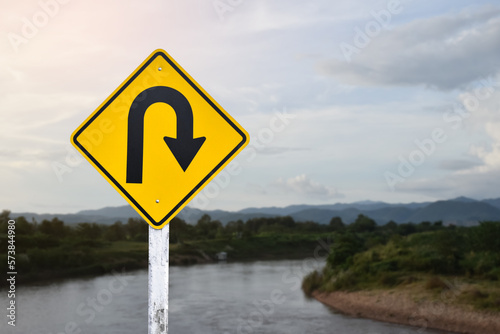 Traffic sign: Right U-turn sign on cement pole beside the rural road with white cloudy bluesky background, copy space. 