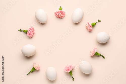 Frame made of Easter eggs and carnation flowers on pink background