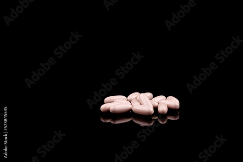 Medical concept of prescription pills and capsules on black background, with reflection, copy space