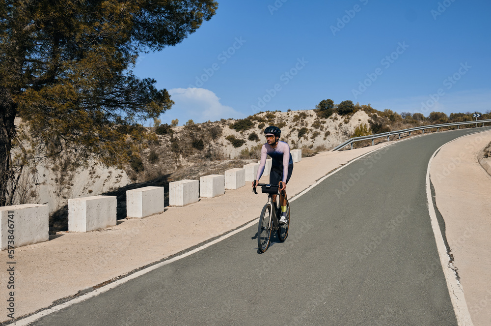 A male cyclist riding a gravel bike downhill on a mountain road.Beautiful motivation image of an athlete.