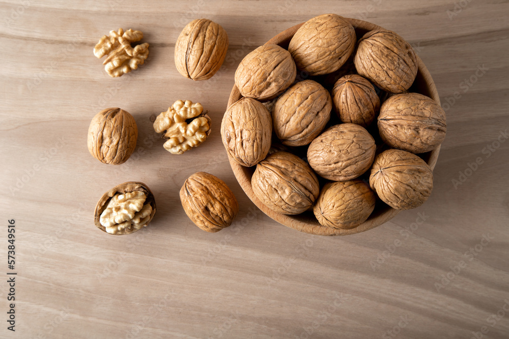 Peeled walnuts and whole walnuts in wooden bowl,top view Peeled walnuts and whole walnuts in wooden bowl,top view
