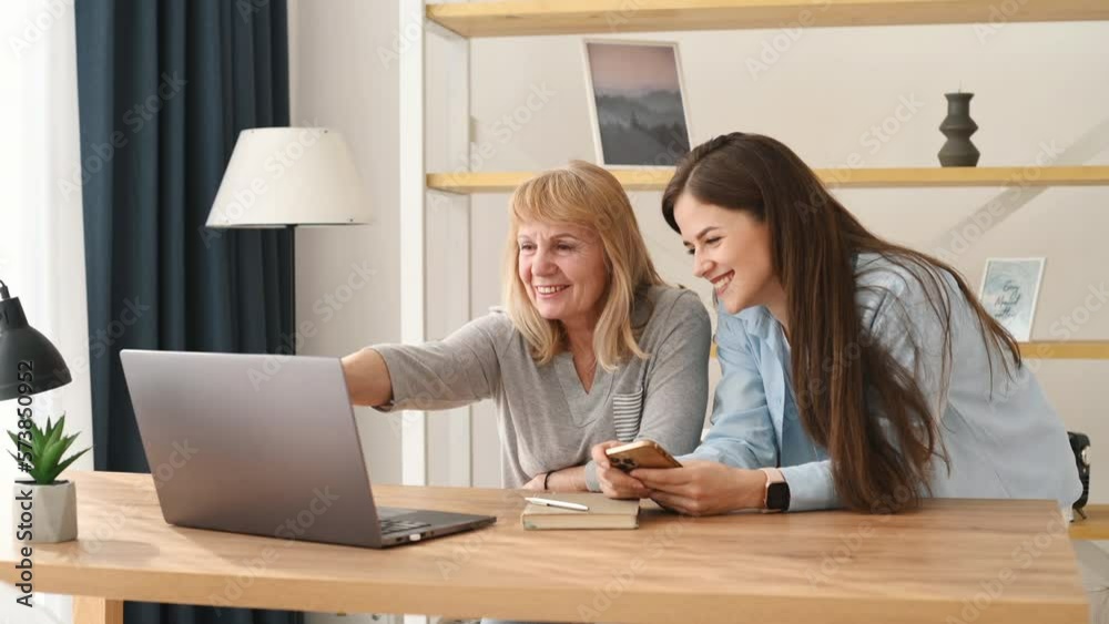 Sitting and using laptop. Mother and daughter is together indoors. Sitting and using laptop. Mother and daughter is together indoors.