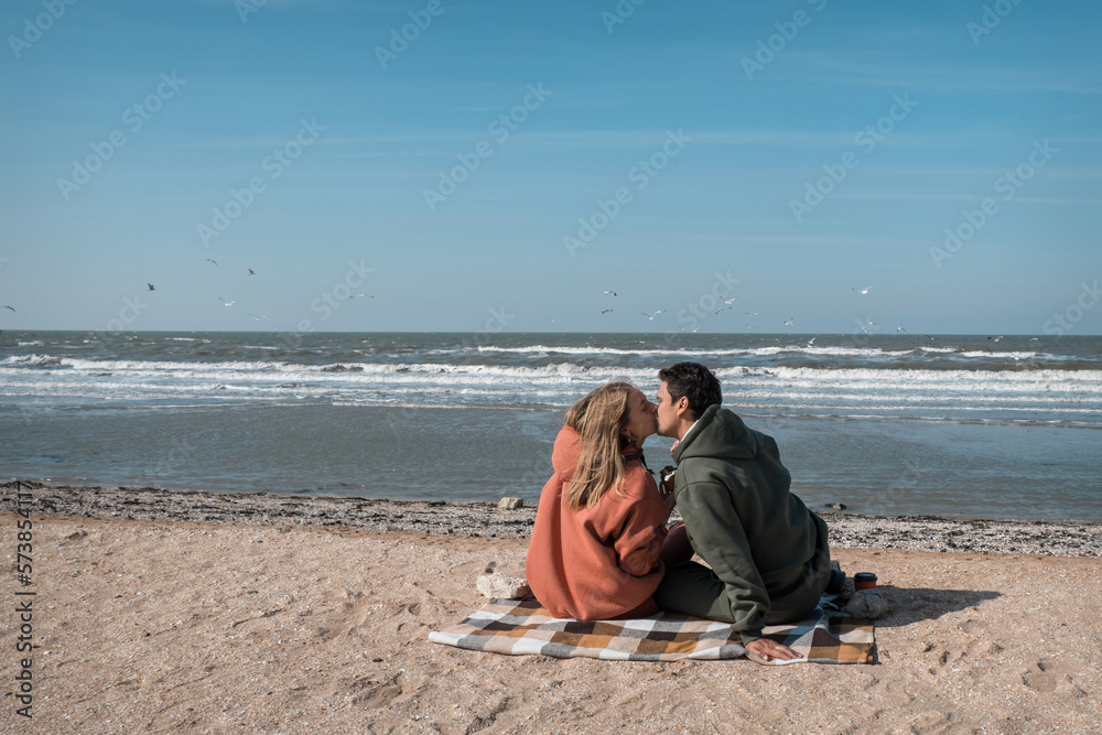 The guy and the girl hug and look at each other with love on the beach, against the backdrop of the Blue Sea. Tender relationship of husband and wife. The date of the young couple on Valentine's Day