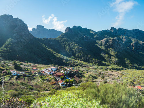 Dramatic lush green picturesque valley with old village Los Carrizales . Landscape with sharp rock formation, hills and cliffs seen from mountain road, Tenerife, Canary Islands, Spain. sunny winter photo