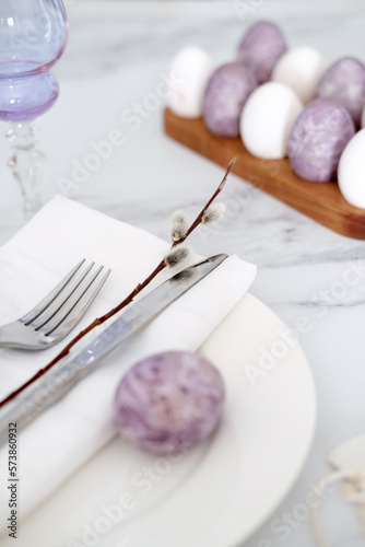 Close-up of Easter table setting with purple decorations, willow branches and eggs
