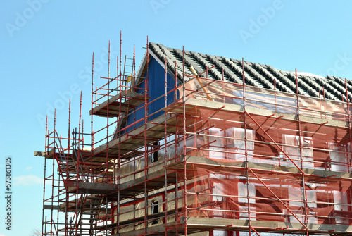 Building Under Construction with Metal Scaffolding on Summer Day with Blue Sky