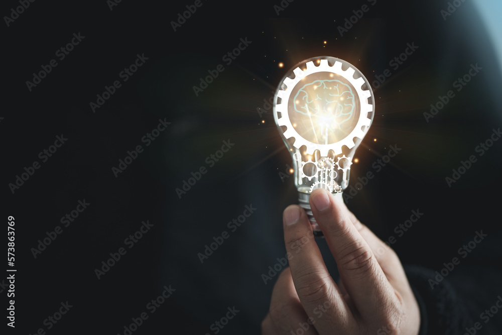 hand of a man with a light bulb And there is a gear icon in it And he is using a notebook computer. The idea of ​​inspiration from online technology. innovation idea concept.