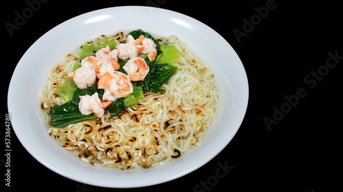 Noodle Soup with Shrimps and vegetable in white bowl isolated on black background. Traditional asian noodle soup.