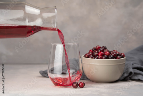 Glass with healthy cranberry juice on light background