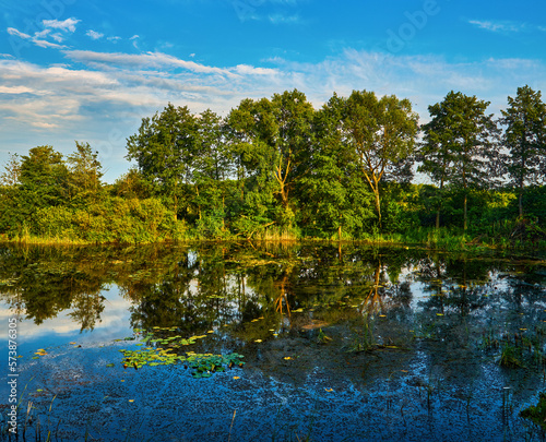 Fototapeta Naklejka Na Ścianę i Meble -  Beautiful scenic view at nice landscape on a beautiful lake and colorful sunset with reflection on water with green gras on foreground and glow on a background