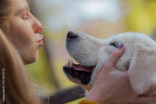 Beautiful young woman playing with golden retriever outdoors. Cute hipster girl hugs and kissed her dog.