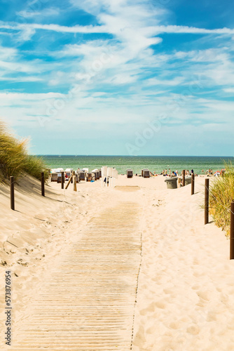 Fototapeta Naklejka Na Ścianę i Meble -  Bbeach sand, blue sky with clouds, beach chairs. People are sunbathing. The beach of the Baltic Sea, Germany resort.