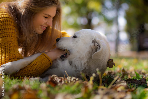 Belgrade, Serbia. November 10th, 2022. Cheerful young woman playing with her golden retriever in the ground of a park. Sunny day fun.