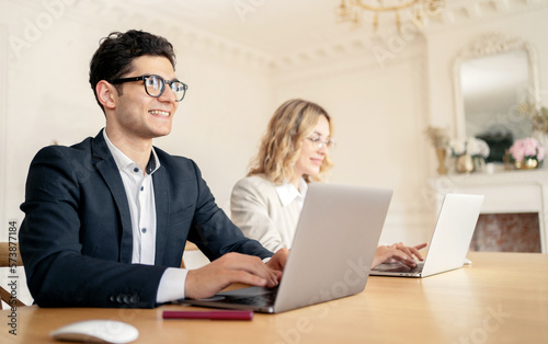 Using laptops computer brainstorming in the office, a man and a woman are successful partners managers in business suits.